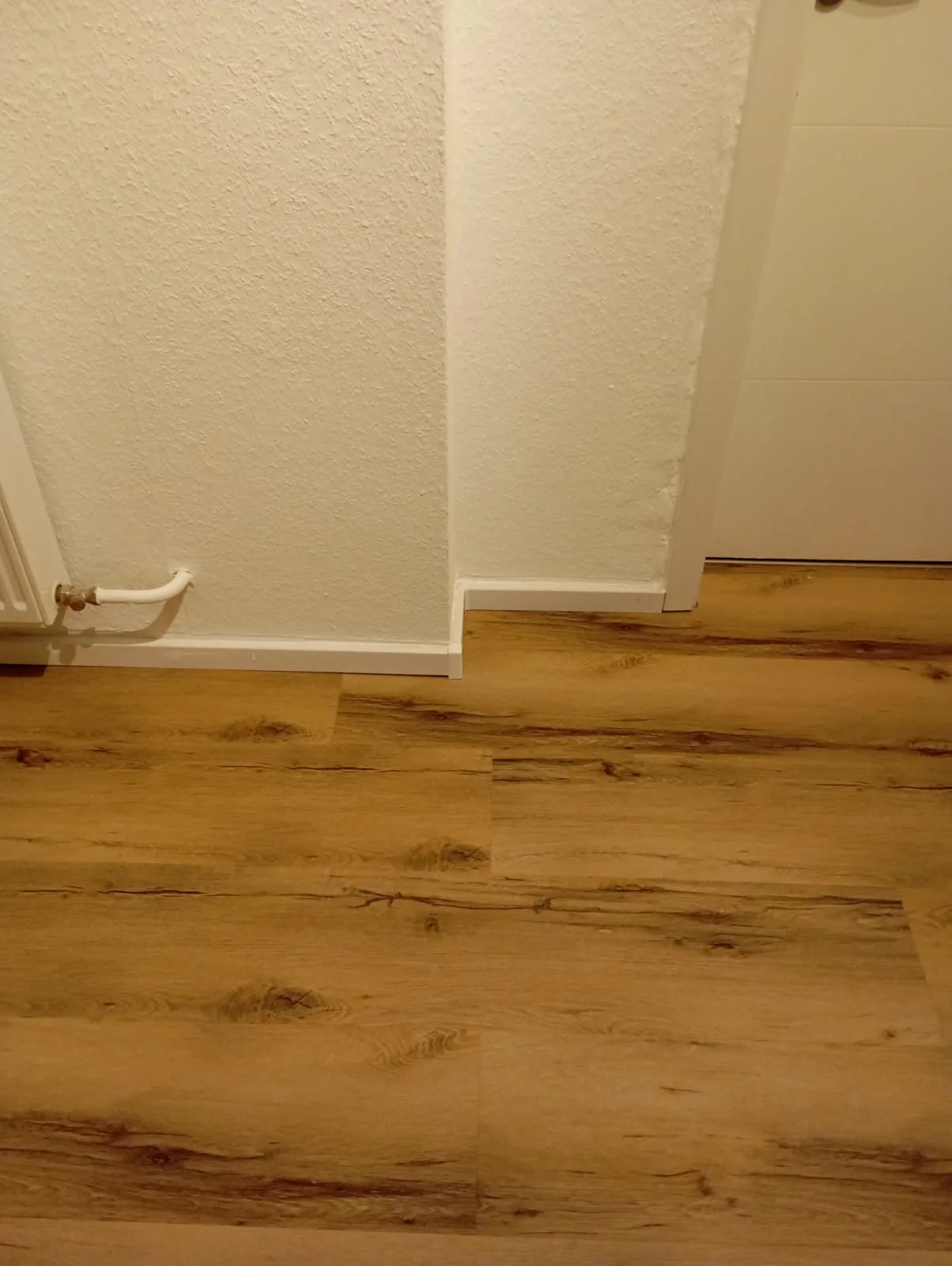 Blick auf einen neu verlegten Boden mit Holzimitation und nahtloser Übergang zur Wand