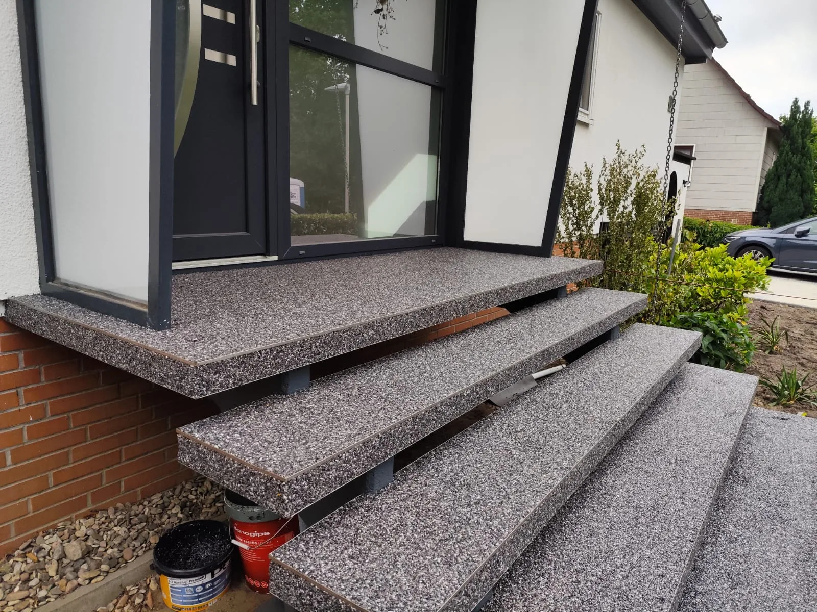 Steinteppich Treppe aus grauem Material vor einem Eingangsbereich