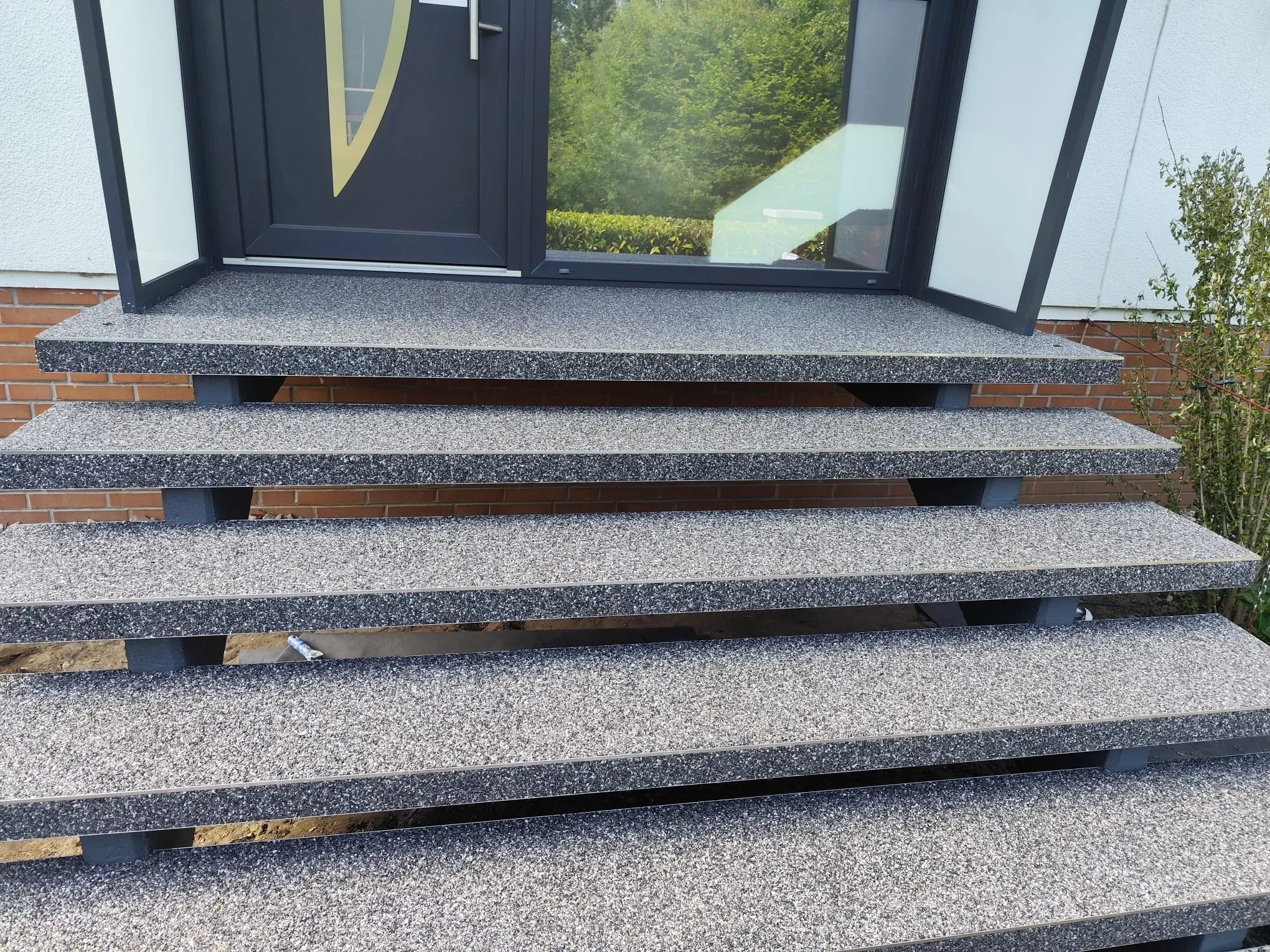 Steinteppich auf einer Terrasse mit mehreren Stufen vor einer Eingangstür