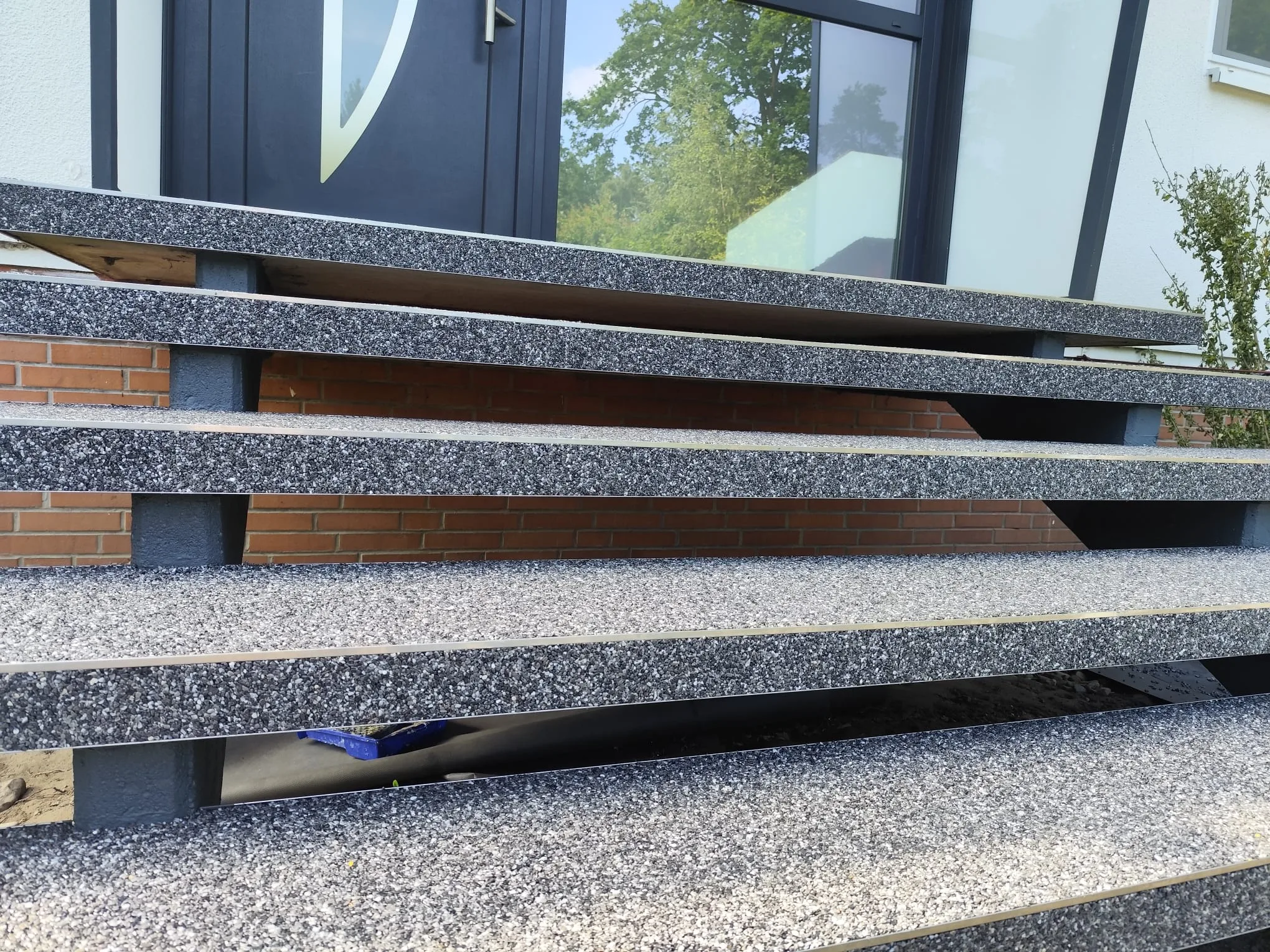 Steinteppich Treppe mit lichtgrauer Oberfläche vor einem Eingang